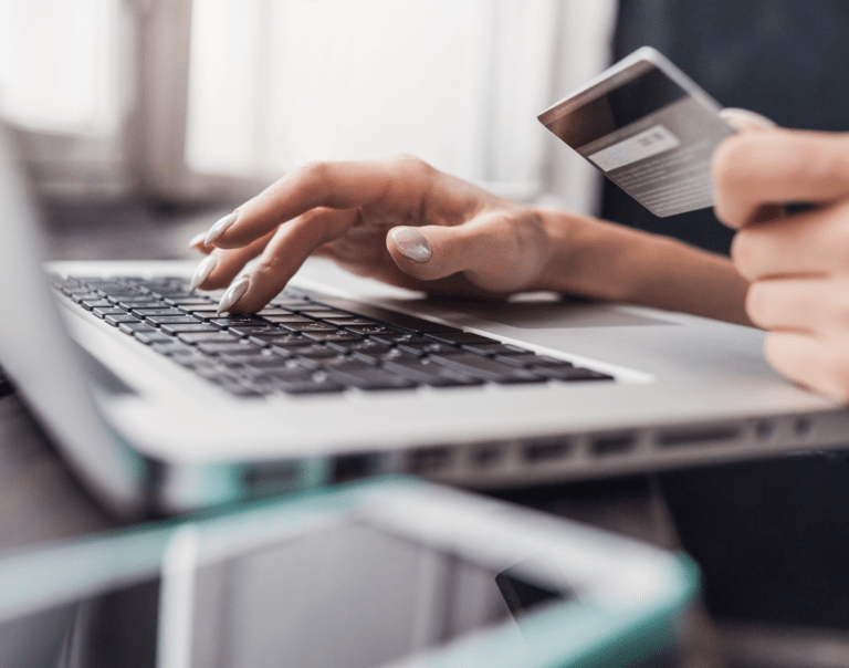 Woman typing on keyboard holding a credit card