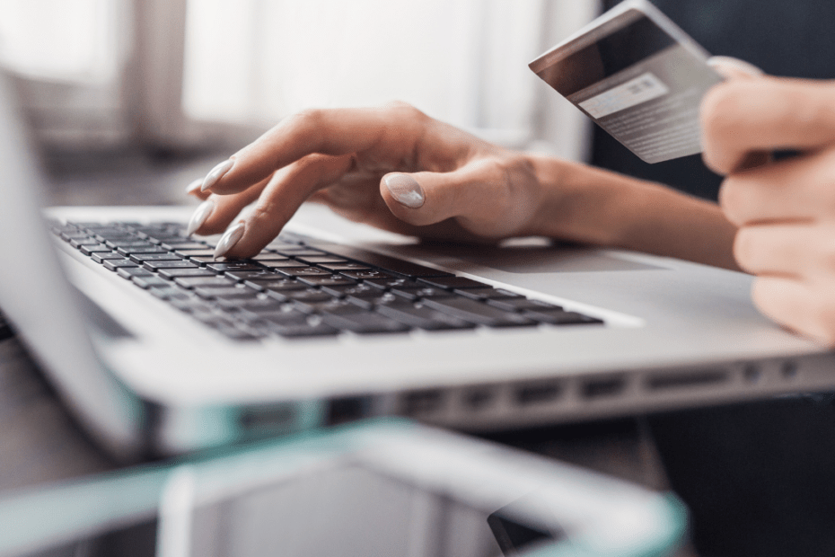 Woman typing on keyboard holding a credit card