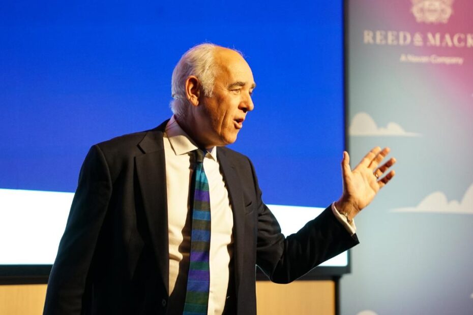 Speaker at a conference in front of a digital screen