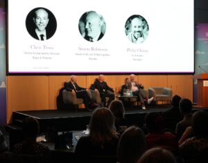 Panellists sat on stage in front of a powerpoint presentation